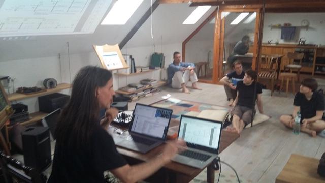 Presenter with two laptops explaining to participants sitting on the floor