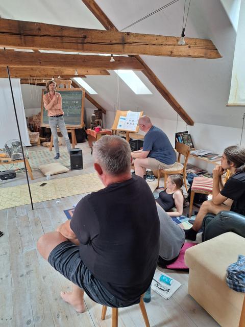 Speaker at a blackboard with musical notation, audience listening
