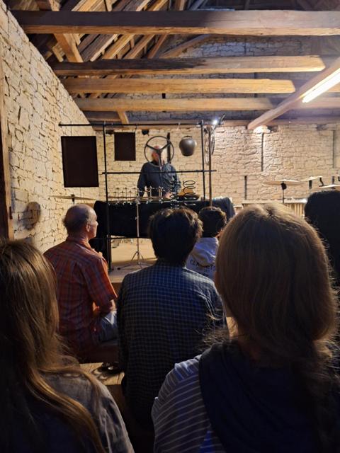 Performer behind a frame of hanging percussion instruments, audience in front