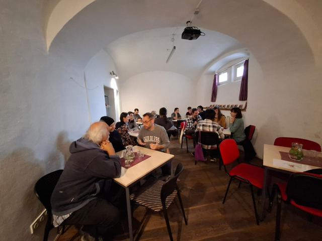 Participants talking at small tables in a vaulted room