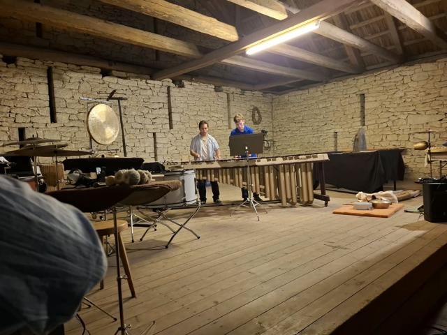 Two musicians playing a marimba in a stone barn